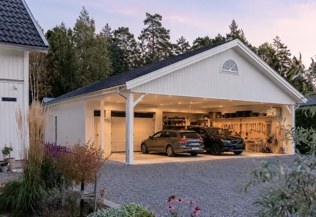 Vitt garage med två bilar, verktyg och förvaring. En vacker plats att bygga carport.